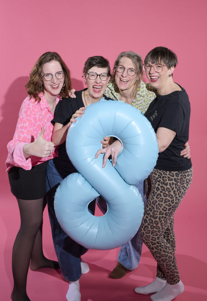 Gruppenfoto von vier Mitgliedern bei dasBUUSENKOLLEKTIV, in der Hand halten sie eine 8